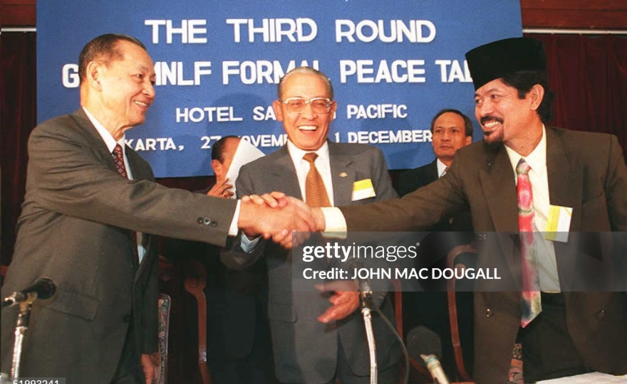 JAKARTA, INDONESIA - NOVEMBER 27: Head of the Moro National Liberation Front (MNLF) delegation Professor Nur Misuari (R) and Manuel T. Yan (L), head of the Philippines Governnment delegation shake hands as Indonesian Foreign Minister Ali Alatas looks on prior to the inaugural session of the 3rd round of formal peace talks 27 November aimed at achieving autonomous status for the southern Philippines island of Mindanao. The peace talks are scheduled to last for four days. AFP PHOTO (Photo credit should read JOHN MACDOUGALL/AFP via Getty Images)
